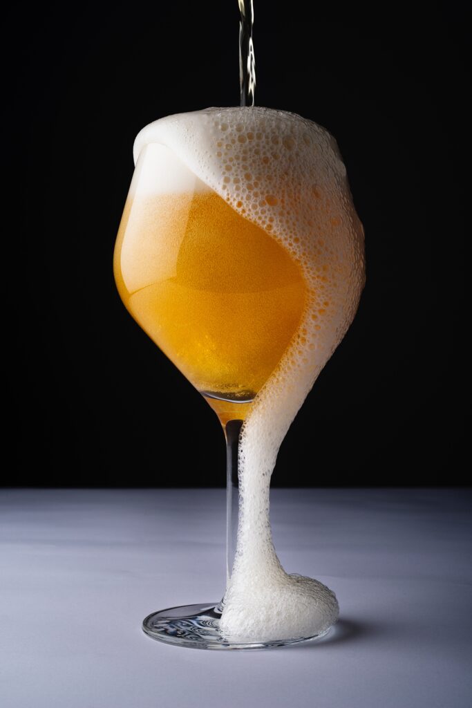 Beer overflowing from the glass.